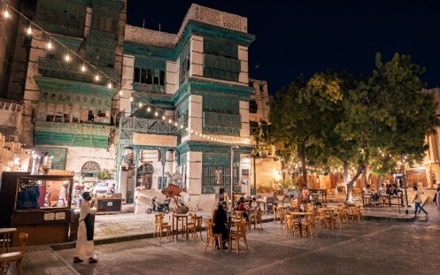 A group of people sitting at tables outside a building Description automatically generated