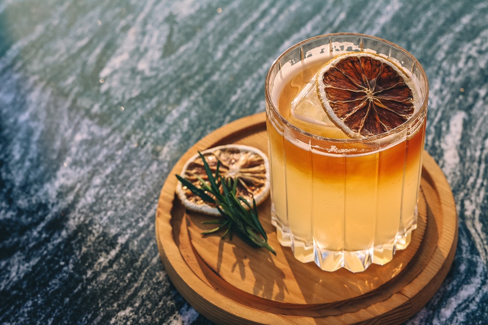 A glass of drink with a slice of orange on a wooden tray
AI-generated content may be incorrect.